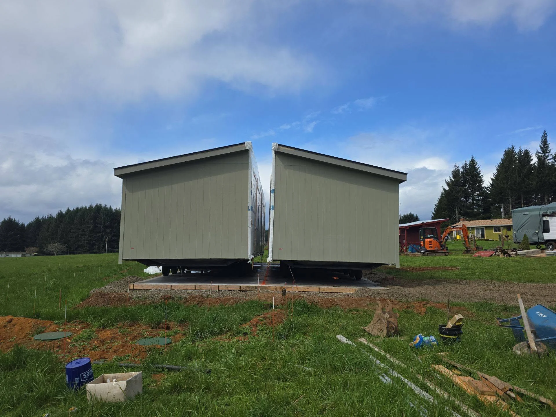 Two modular metal buildings with light siding installed on timber foundation and gravel pad