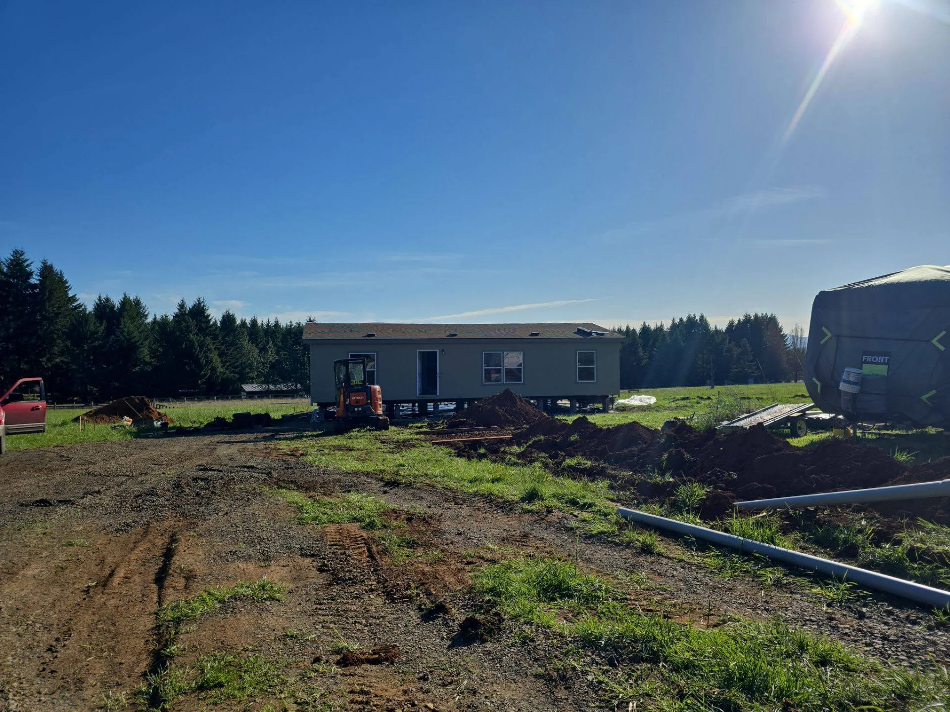 Mobile home installation with excavation, graded site, and underground utility lines in progress