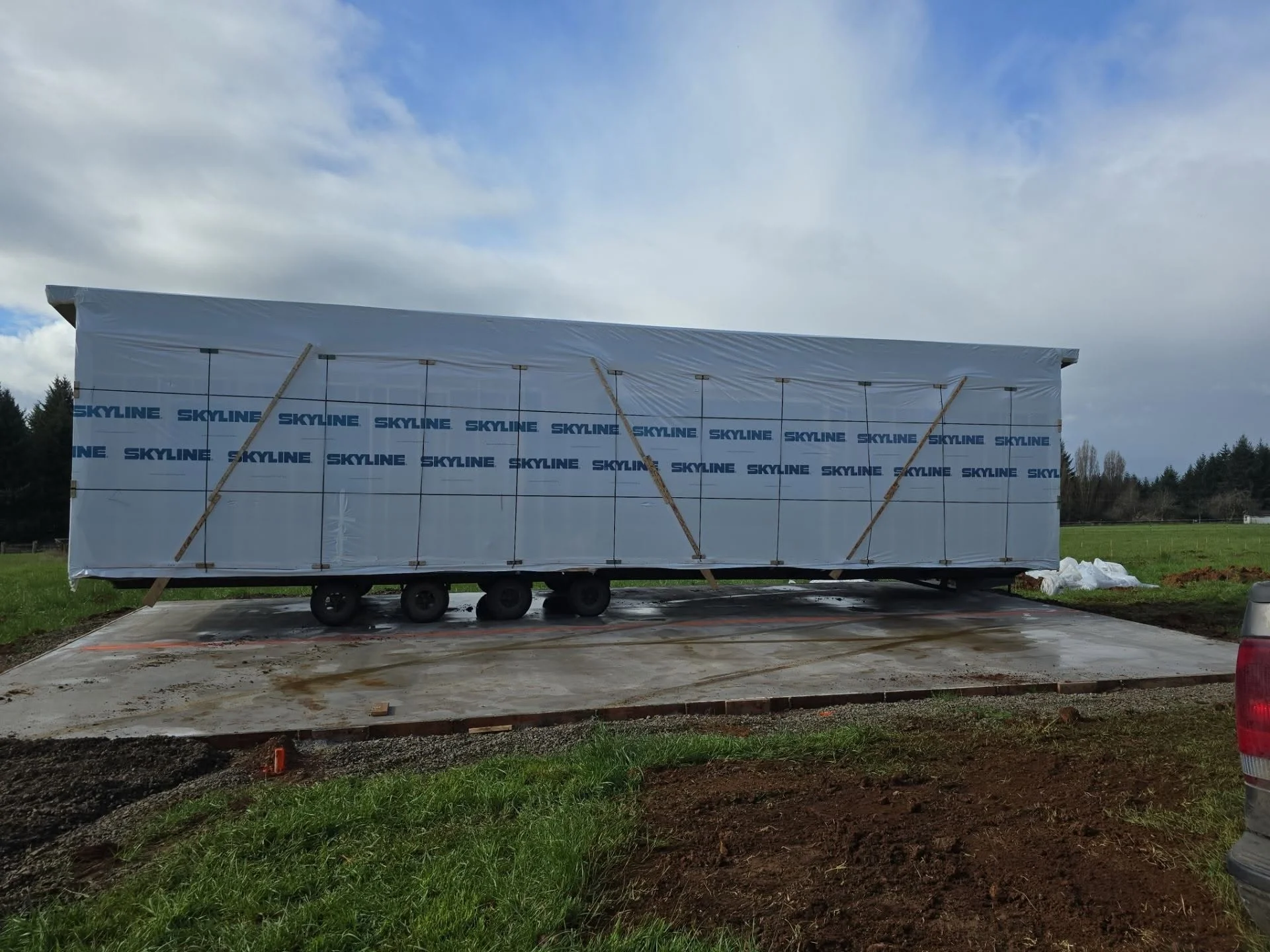 Concrete foundation pad with agricultural trailer on prepared ground, gravel and soil work visible