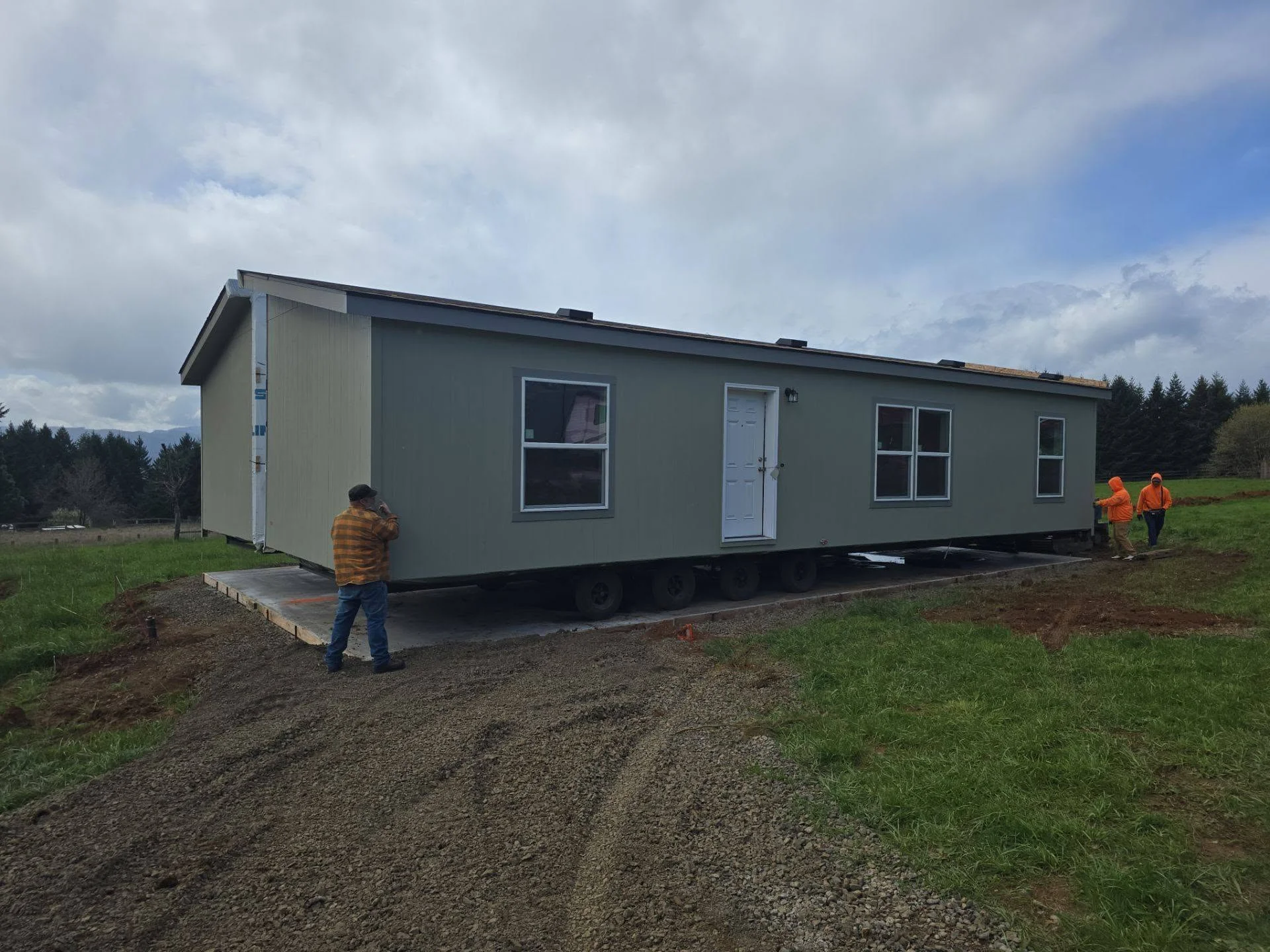 Mobile home installation on gravel foundation with metal siding and vinyl windows