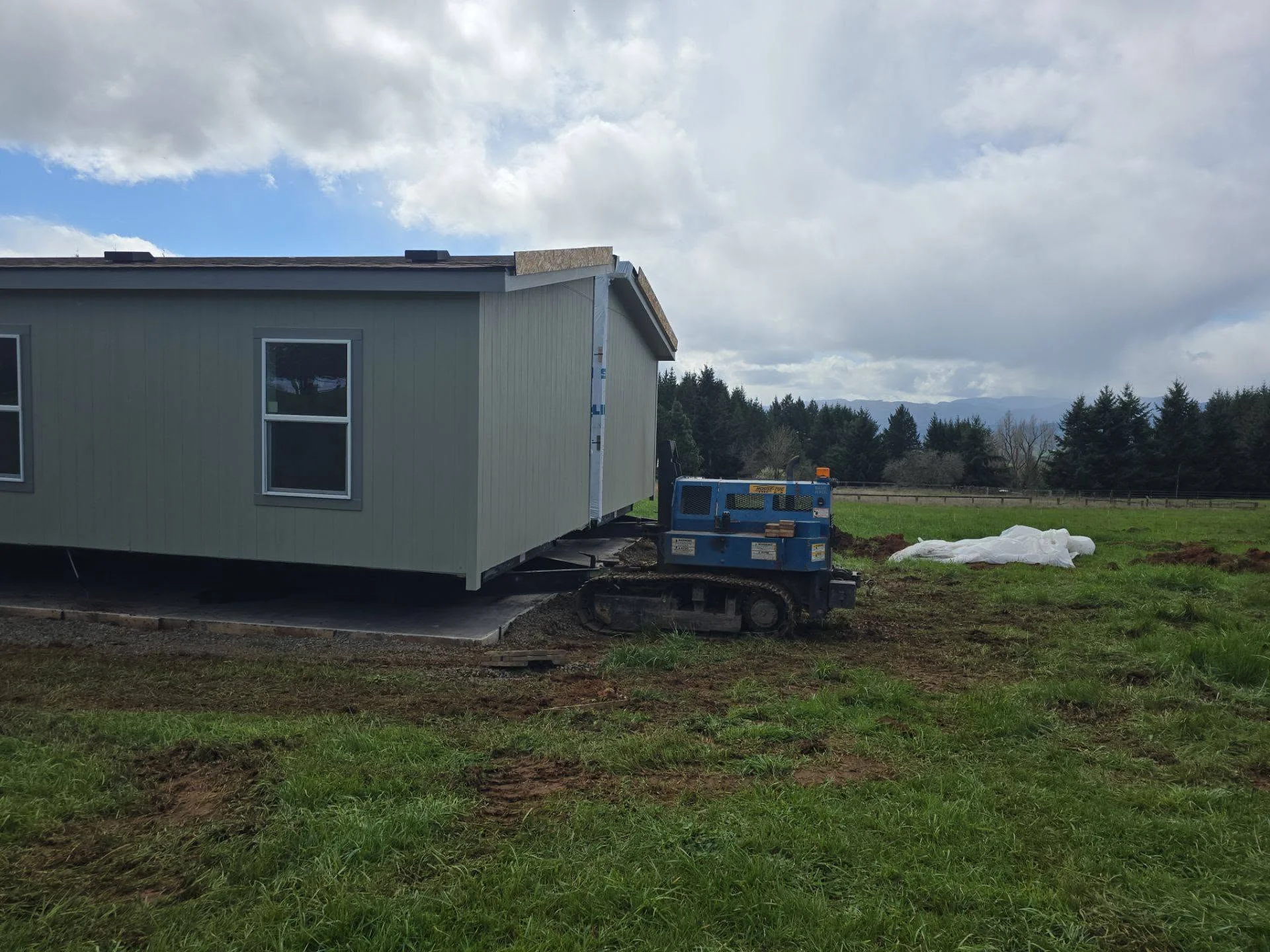 Mobile home installation on concrete foundation with metal siding and site grading work