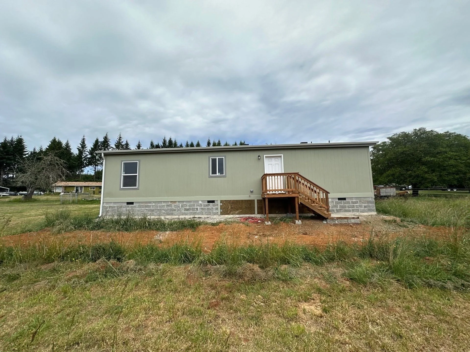 Mobile home on concrete block foundation with vinyl skirting and wooden deck with railings