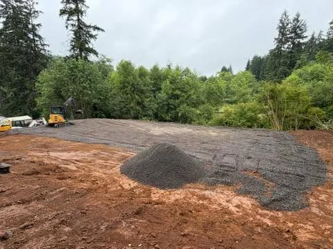 Freshly graded gravel driveway with compacted base material and surrounding excavated earth