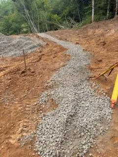 Gravel driveway with compacted stone base and cleared earthwork on sloped terrain