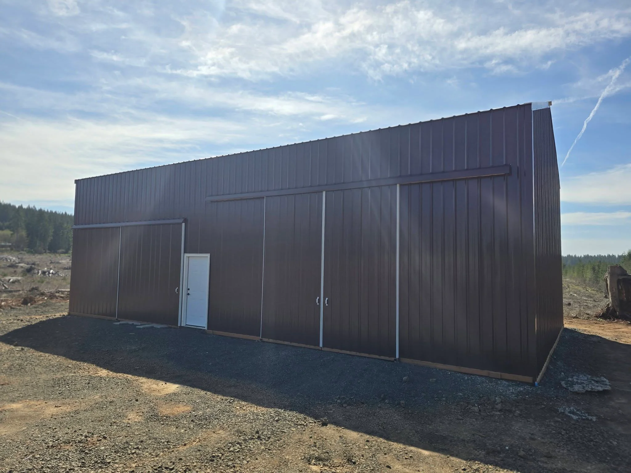 Charcoal gray corrugated metal building with sloped roof and multiple garage doors