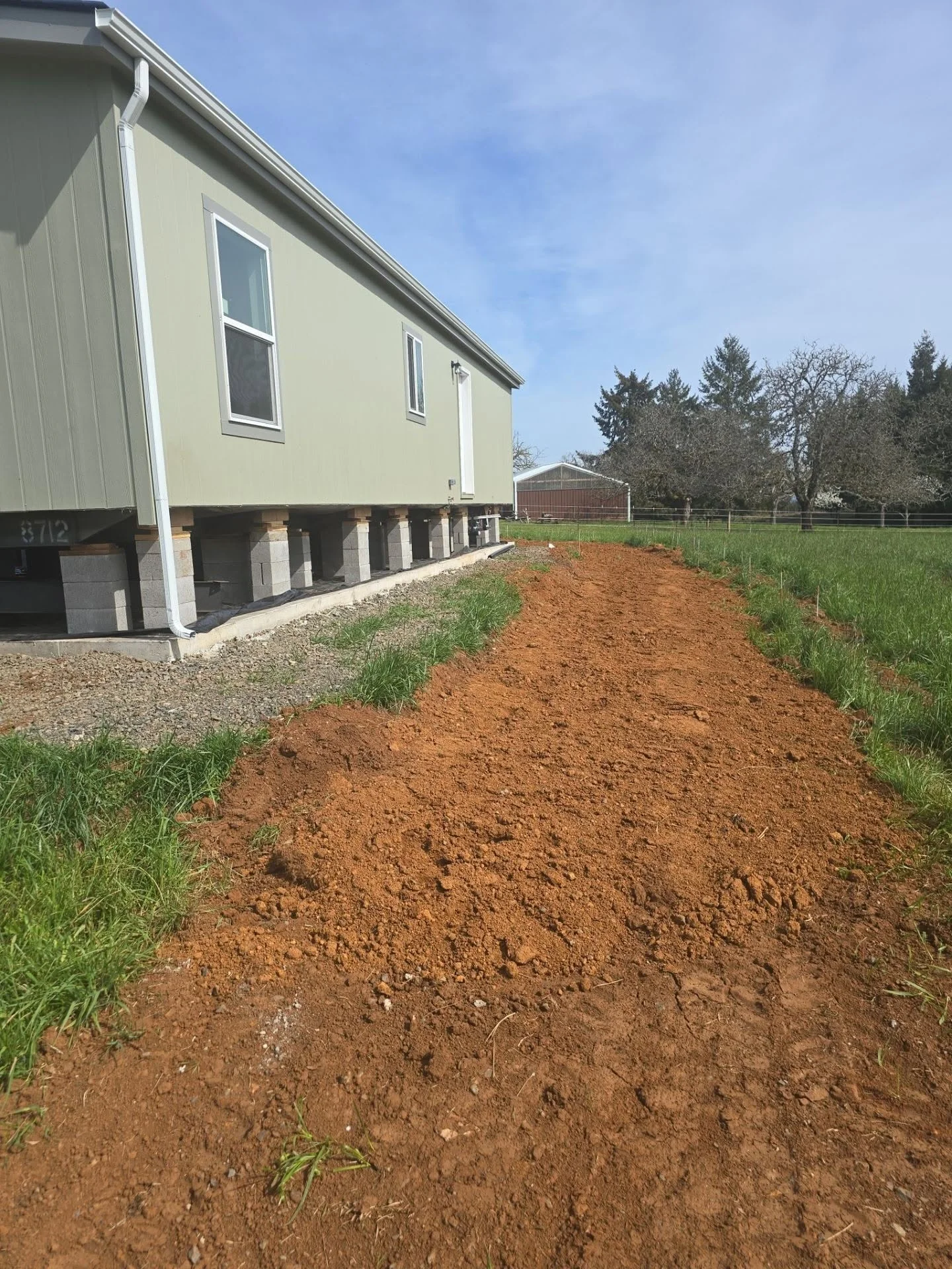 Mobile home on concrete pier foundation with freshly excavated and graded dirt pad