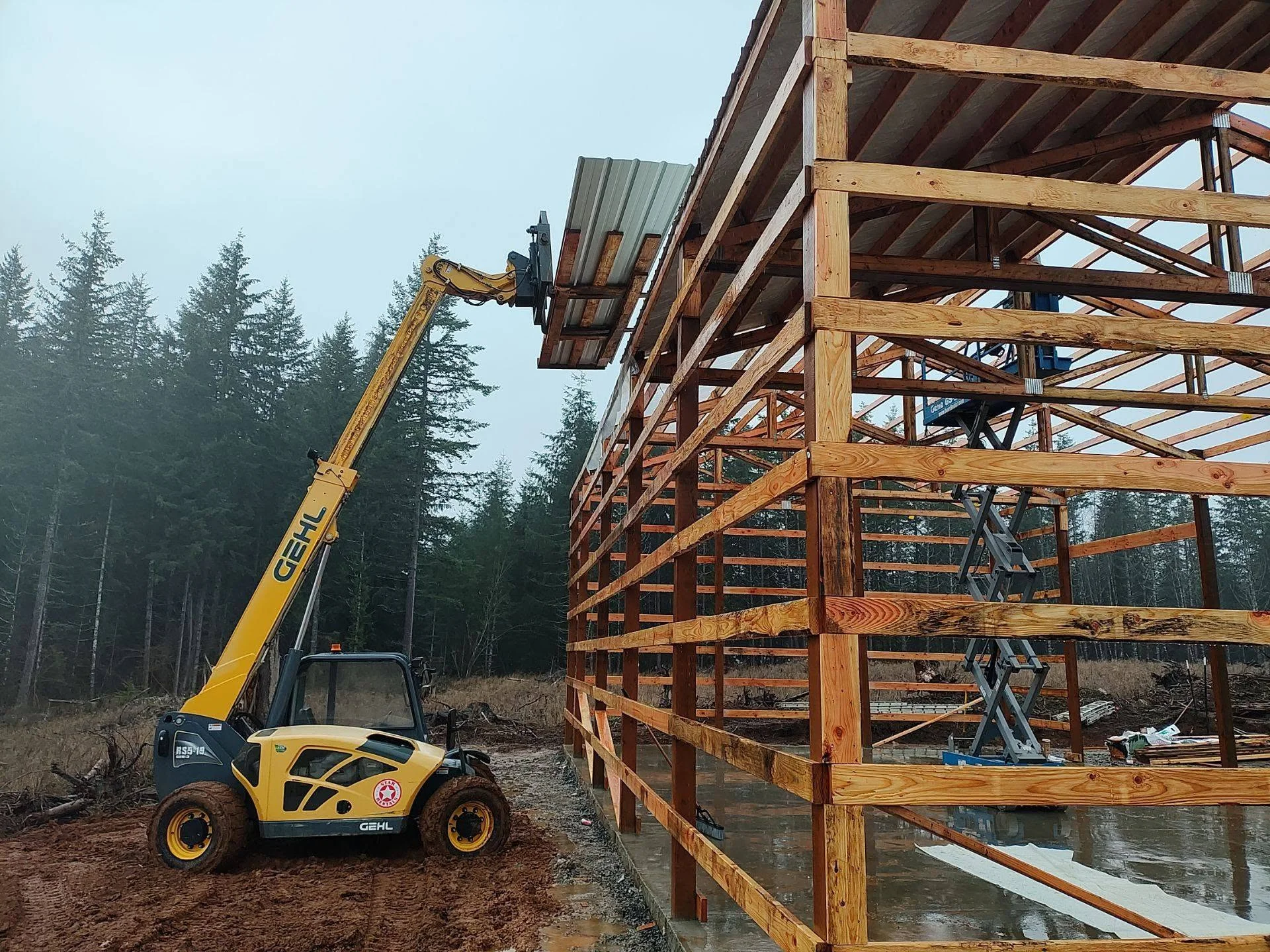 Timber frame construction with heavy beams, metal roofing, and telescopic handler positioning materials