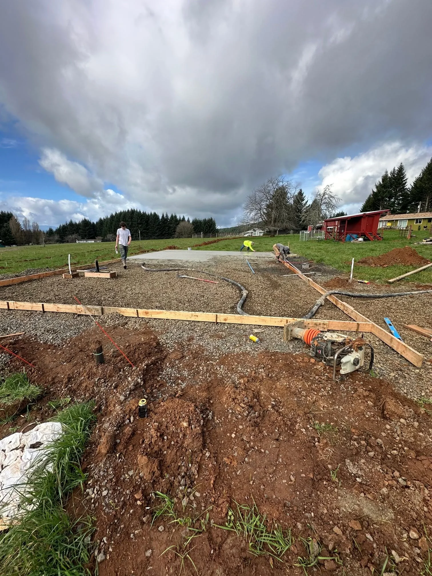Excavation site with gravel base, wooden forms, and soil grading on rural property